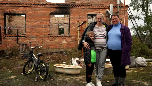 A 6-year-old boy stands with his mother and grandmother outside the house that was destroyed during a heavy shelling attack in Shybene, Kyiv oblast, Ukraine.