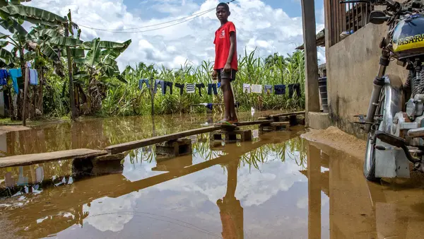 Peretimfa, 11, stands on a makeshift wooden walkway over floodwaters outside his home in Sagbama, Bayelsa State, Nigeria. 