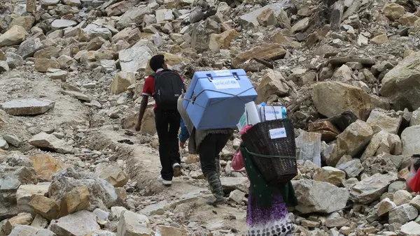 Health care workers carry UNICEF-provided vaccines on difficult terrains in Barpak Village, Nepal.