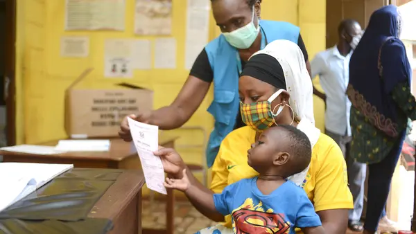 Margaret Gwada of UNICEF Ghana assists a mother who has just received a birth certificate for her child at the Births and Deaths Registry in Tamale.