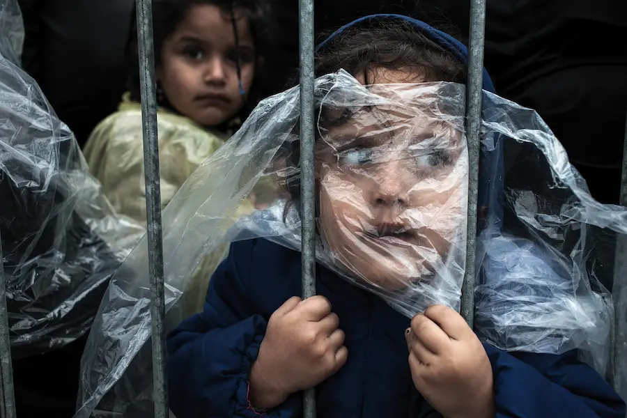 A child refugee is covered with a raincoat while she waits in line at the refugee registration camp in Presevo, Serbia in October 2015. A child refugee is covered with a raincoat while she waits in line at the refugee registration camp in Presevo, Serbia in October 2015.