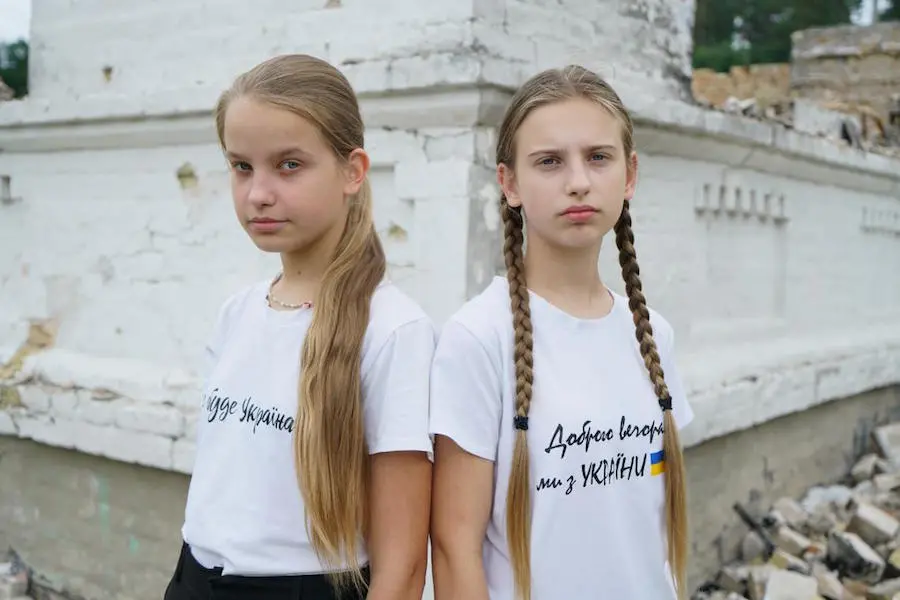 Sisters Liliya, 11, and Nelya, 13, stand in front of their ruined school in Horenka, in the Kyiv region of Ukraine. Sisters Liliya, 11, and Nelya, 13, stand in front of their ruined school in Horenka, in the Kyiv region of Ukraine.