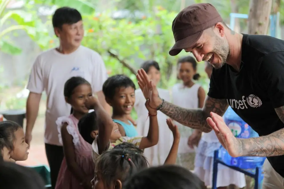 Adult man high five-ing different children while laughing and playing