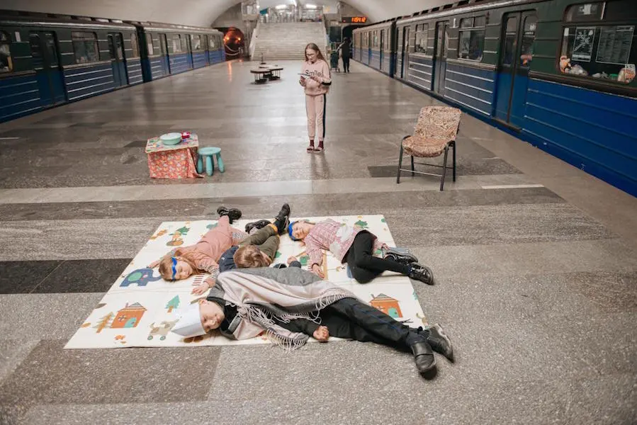 Volunteer teacher Yuliia Kruhlaia, 41, leads children in a warm-up exercise on the platform of a Kharkiv metro station