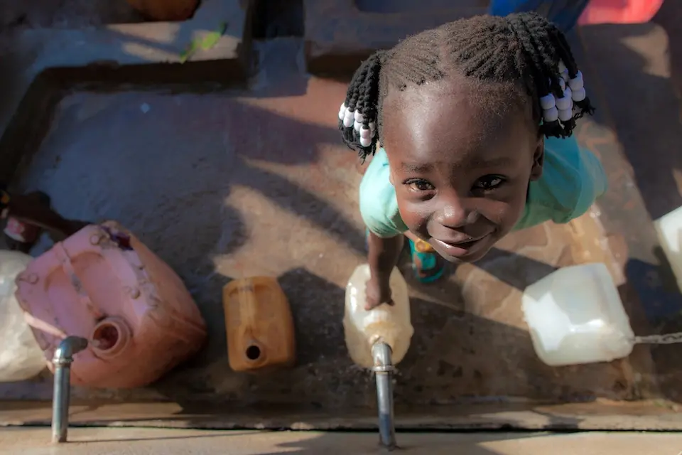 Queen, 5, in Yambio, South Sudan, collects water from a new system outfitted with solar-powered submersible pump.