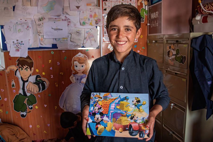 A boy holds a puzzle he worked on at the Child-Friendly Space in the UNICEF-supported Shahrak-Sabz settlement in Herat city for people displaced by conflict.