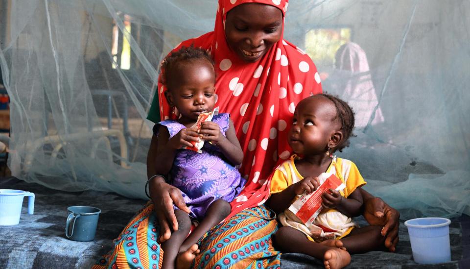 Nana Hadiza, 28, sits with her twin daughters on a bed at Maradi hospital in Niger. The girls are being treated for malnutrition with UNICEF-supplied Ready-to-Use Therapeutic Food (RUTF).