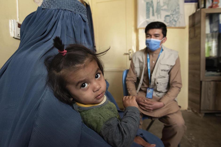 An acutely malnourished 1-year-old girl sits in her mother's lap as they meet with a UNICEF nutrition officer at a UNICEF-supported clinic in Kandahar, Afghanistan to discuss treatment.