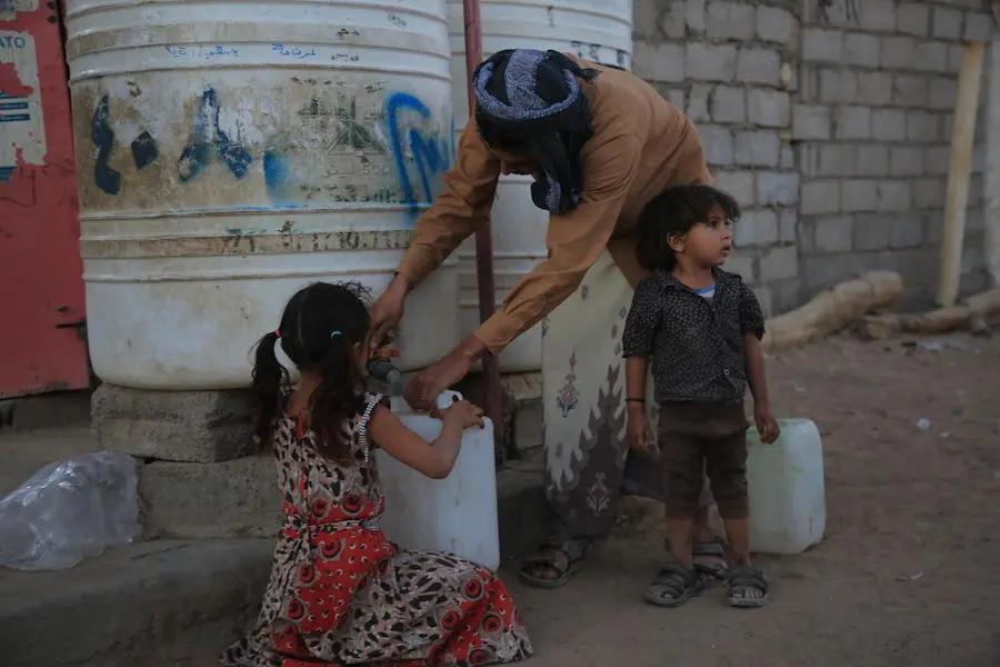 Waleed Al-Ahdal, 25, and his children fetch water to take back to their tent in a camp for internally displaced families in Yemen's Marib governorate.