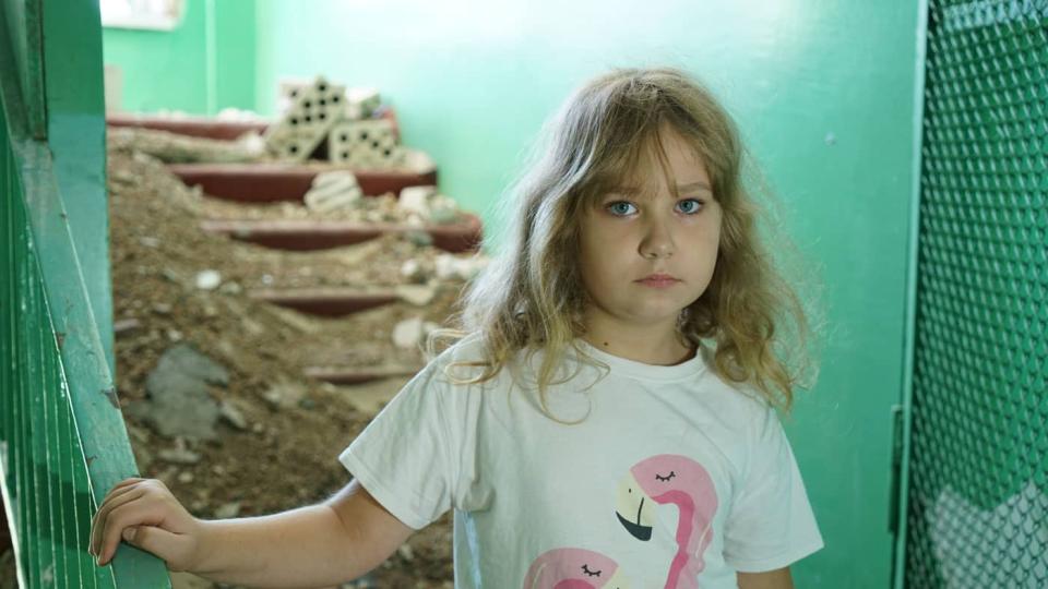 Nastya, 8, of Buzova, Ukraine, stands amid the rubble of her school, which suffered damage during fighting in February and March 2022.