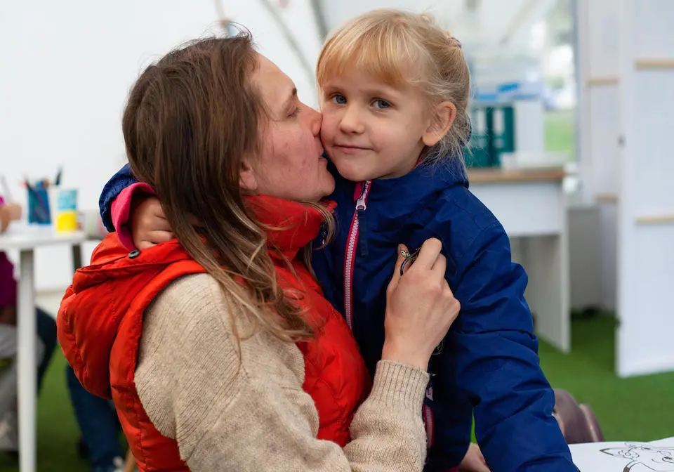 A mother kisses her child goodbye at a UNICEF child-friendly Spilno center in Kyiv, Ukraine.