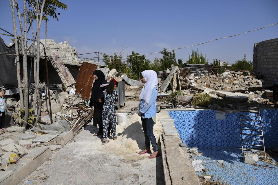 A family views the reconstruction work underway in their yard in Rural Damascus, Syria, after their home was destroyed.