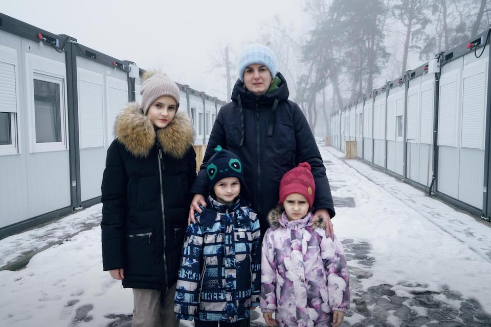 A family stands in the snow outside temporary housing in Irpin, outside of Kyiv, Ukraine.