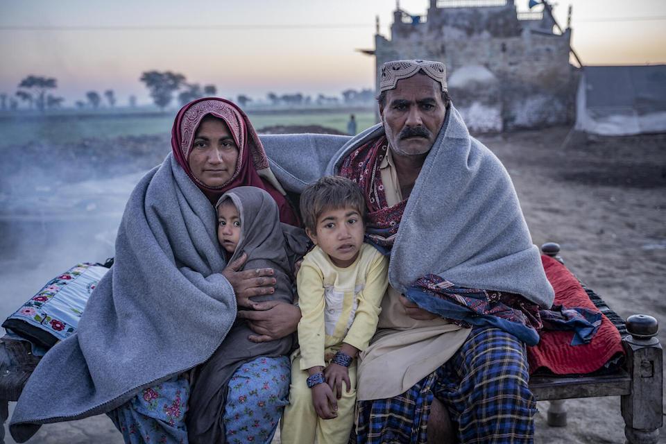 A family sits on a charpoy outside their house after receiving UNICEF’s winter kit in Zangi Brohi Village, Dadu District, Sindh.