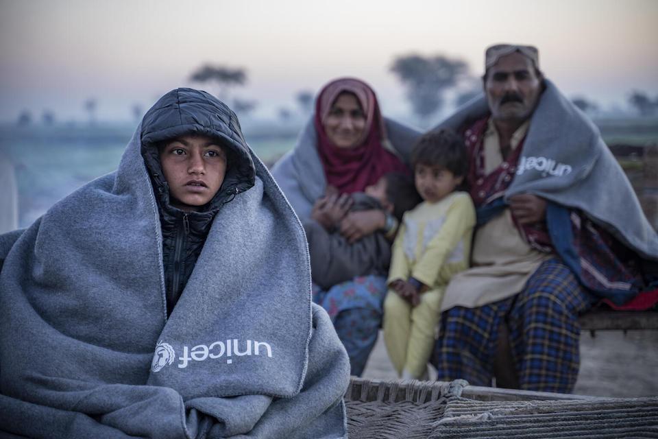 A family sit outside their house after receiving a UNICEF winter kit in Dadu District, Sindh Province, Pakistan.