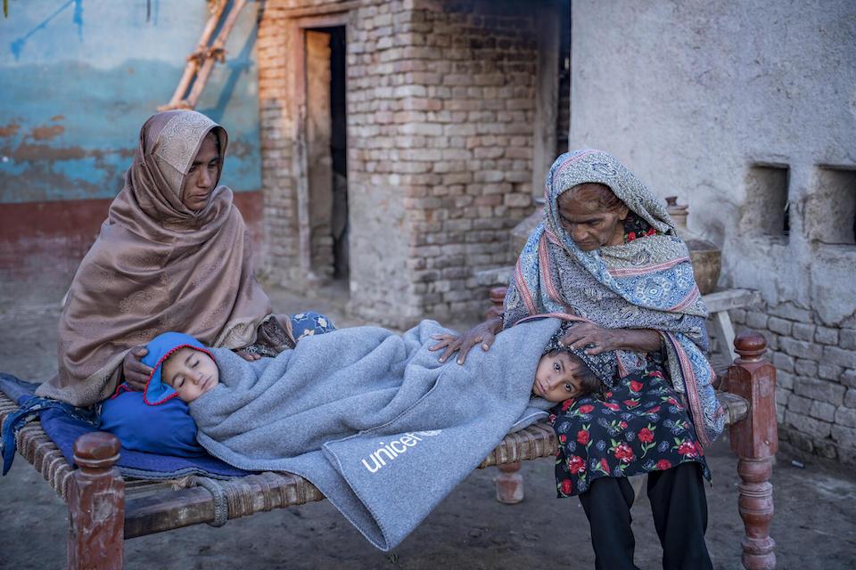 Grandmothers keep their grandchildren warm with the help of blankets provided by UNICEF after flooding in Dadu District, Sindh Province, Pakistan.