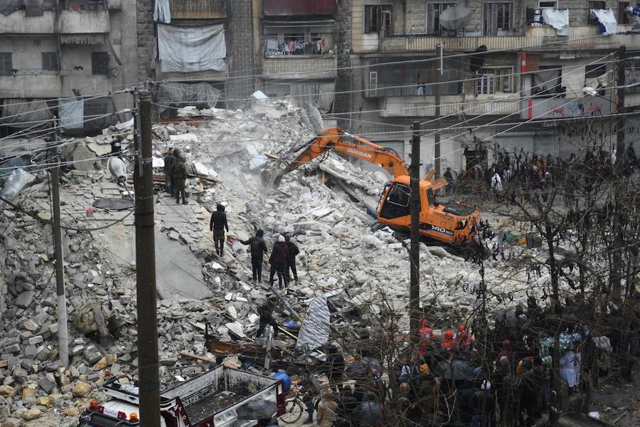 On Feb. 6, 2023, people watch as rescue teams search for survivors under the ruins of a collapsed building in the city of Aleppo in northern Syria, after an early morning earthquake.