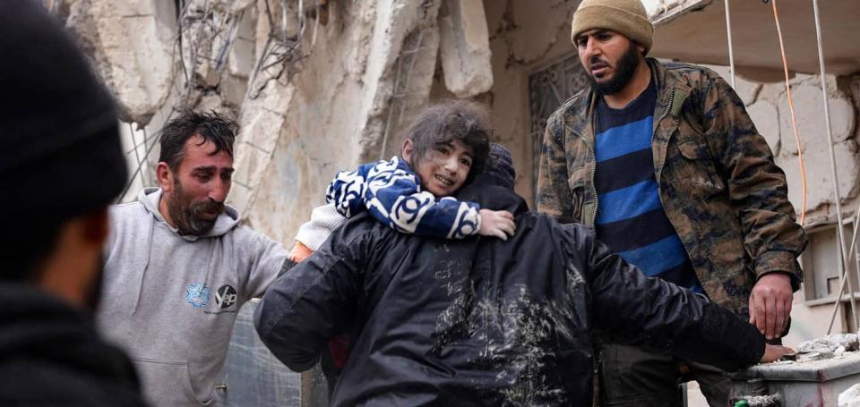 Residents of Jandaris in Syria's Aleppo Province rescue a child from the remains of a building that collapsed during the Feb. 6, 2023 earthquake.