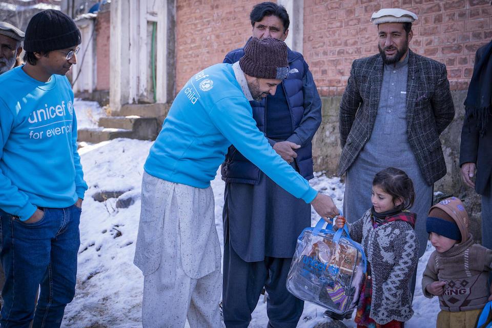 Six-year-old Wajiha receives a UNICEF winter kit from UNICEF Planning, Monitoring and Evaluation Officer Zaheer Ahmad in Sheringal, Upper Dir District, Khyber Pakhtunkhwa, Pakistan.