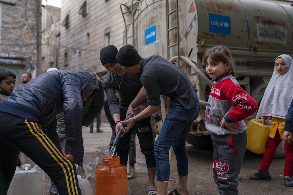 On Feb. 10, 2023, children and families fill jerrycans with safe drinking water at a distribution point in the Almyassar neighborhood of Aleppo city in northern Syria. 
