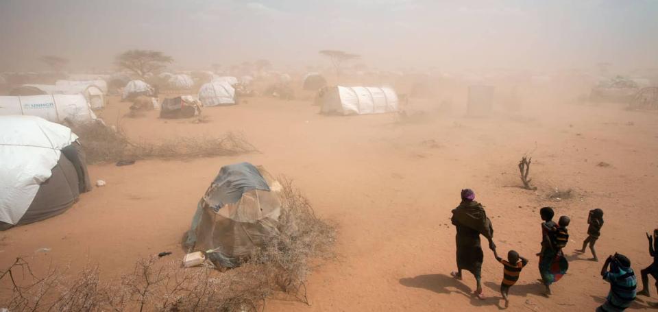 A woman and several children walk through a dust storm to their tent at the Dagahaley refugee camp in Kenya's North Eastern Province, near the Kenya-Somalia border.