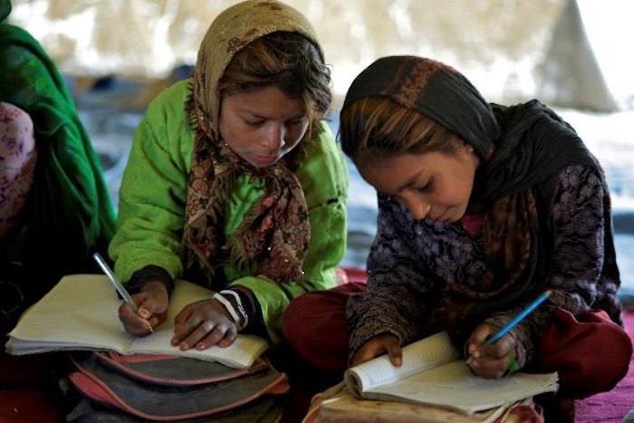 Two girls concentrate on their school work at a community-based school in Afghanistan.