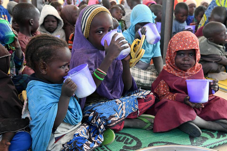 UNICEF-supported child refugees from Nigeria eat a meal inside a crowded tent at the Dar es Salam displacement camp in Chad.