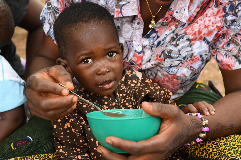 A child samples some nutrient-fortified porridge his mother learned to make at a malnutrition screening session in the village of Ngolo, in northern Burkina Faso. 
