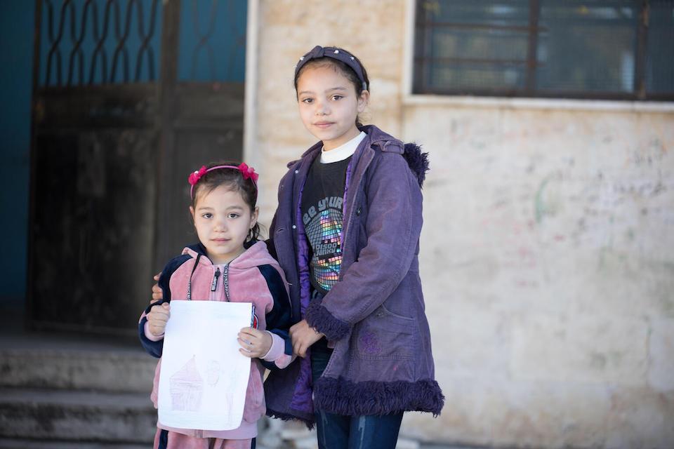 Sisters Renad, 6, and Maysaa, 13, stand outside their shelter in Stamo village, located in Syria's Lattakia governorate.