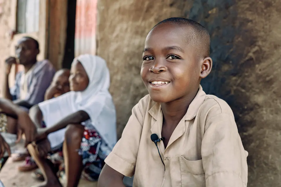 Abasse, 8, sits with his family outside of their home in Tanguieta, northern Benin. The family fled their village in southeastern Burkina Faso when it was attacked.