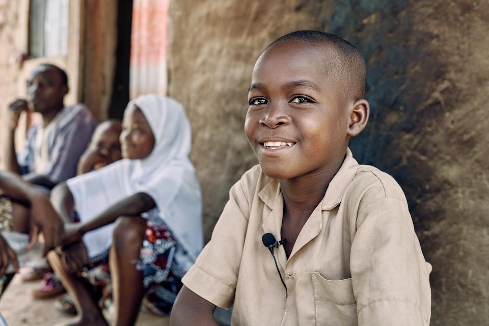 Abasse, 8, sits with his family outside of their home in Tanguieta, northern Benin. The family fled their village in southeastern Burkina Faso when it was attacked. 