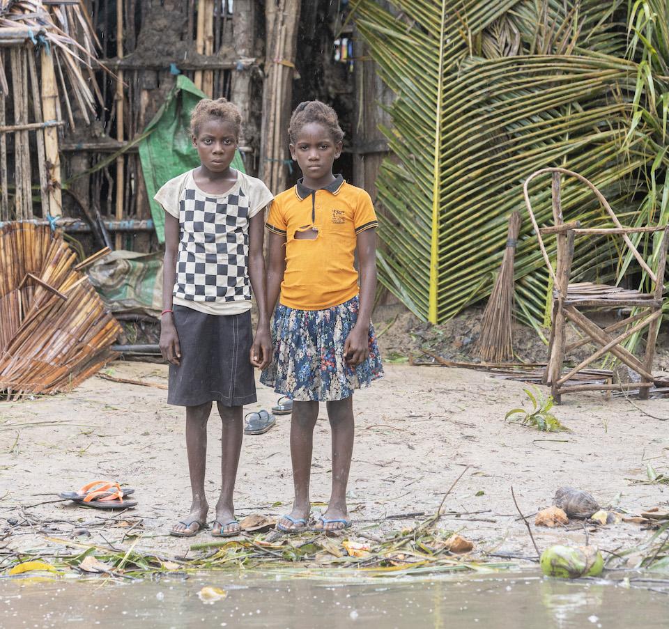 Two sisters, Dercia, 12, and Dusma, 10, standing amidst the wreckage of their flooded village located 35 km outside the city of Quelimane, Mozambique, on March 13, 2023, the day after Tropical Cyclone Freddy made landfall a second time.