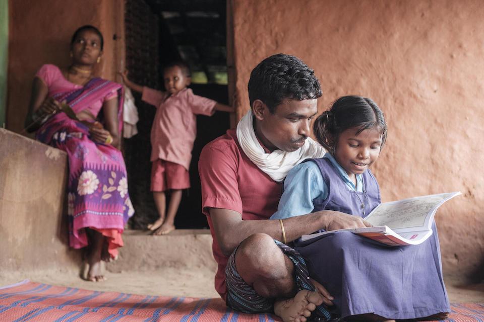 In the Tirathgarh Village of Bastar, Chattisgarh, India, 9-year-old Gumeshwari reads with her father, Mahadev. 