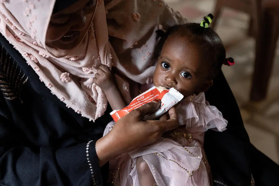 On Oct. 4, 2022 at a UNICEF-supported health center in South Darfur, Sudan, mother Najwa Muhammad Yunis feeds her 13-month-old child, Rudat, Ready-to-Use Therapeutic Food (RUTF).