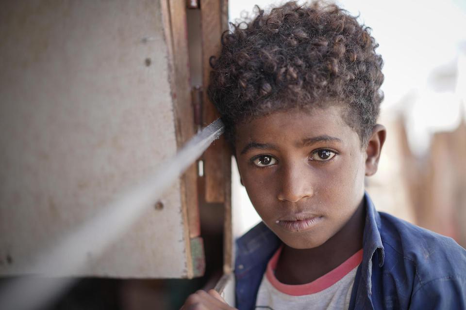 Muhammed, 7, stands in the doorway of his family’s shelter at Al Sha’ab Camp in Aden, Yemen.
