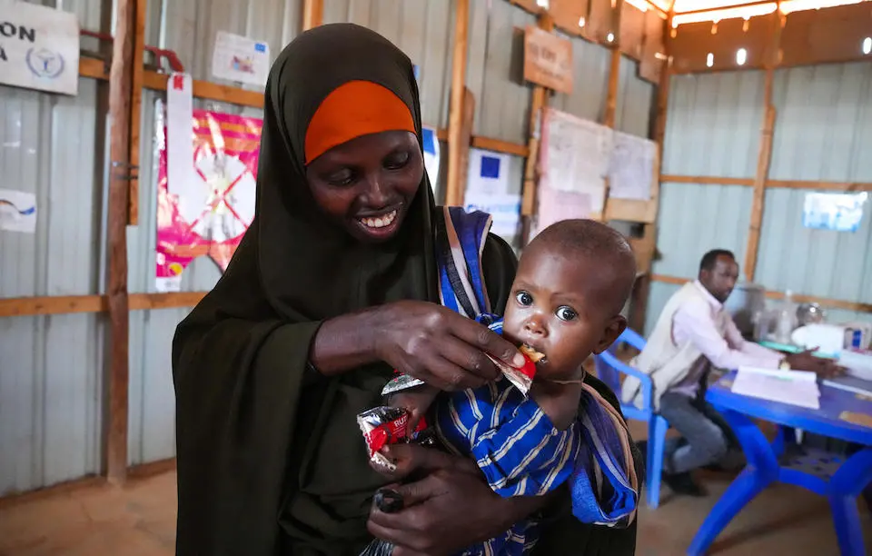 A mother feeds her malnourished child with Ready-to-Use Therapeutic Food at UNICEF-supported Dollow Health Center in Somalia.