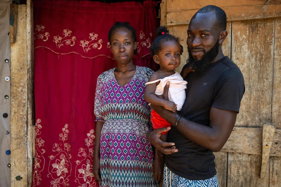 After a devastating earthquake, a family stands outside their shelter In the village of Troirac near Camp-Perrin, Haiti, on July 19, 2022,