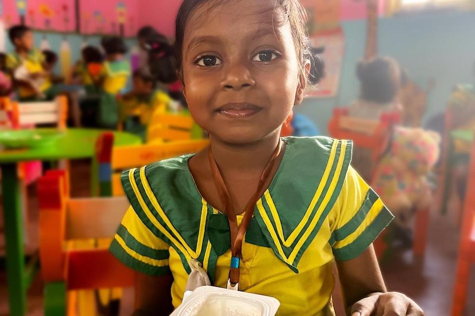 A 5-year-old girl in Sri Lanka enjoys her school meal provided with UNICEF support.