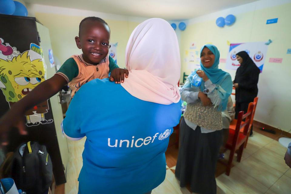 A UNICEF staffer holds a child refugee from Sudan inside a Child-Friendly Space established at a bus station in Aswan, Egypt to serve families who have been displaced by fighting in Sudan.