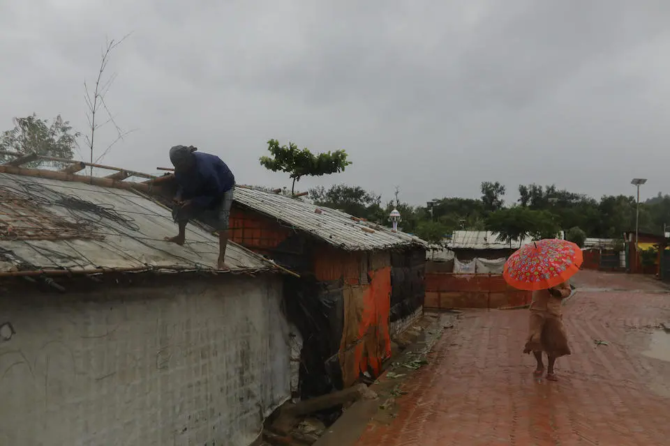 A man tries to fix his roof, damaged by heavy winds during Cyclone Mocha, in Cox's Bazar, Bangladesh, on May 14, 2023.