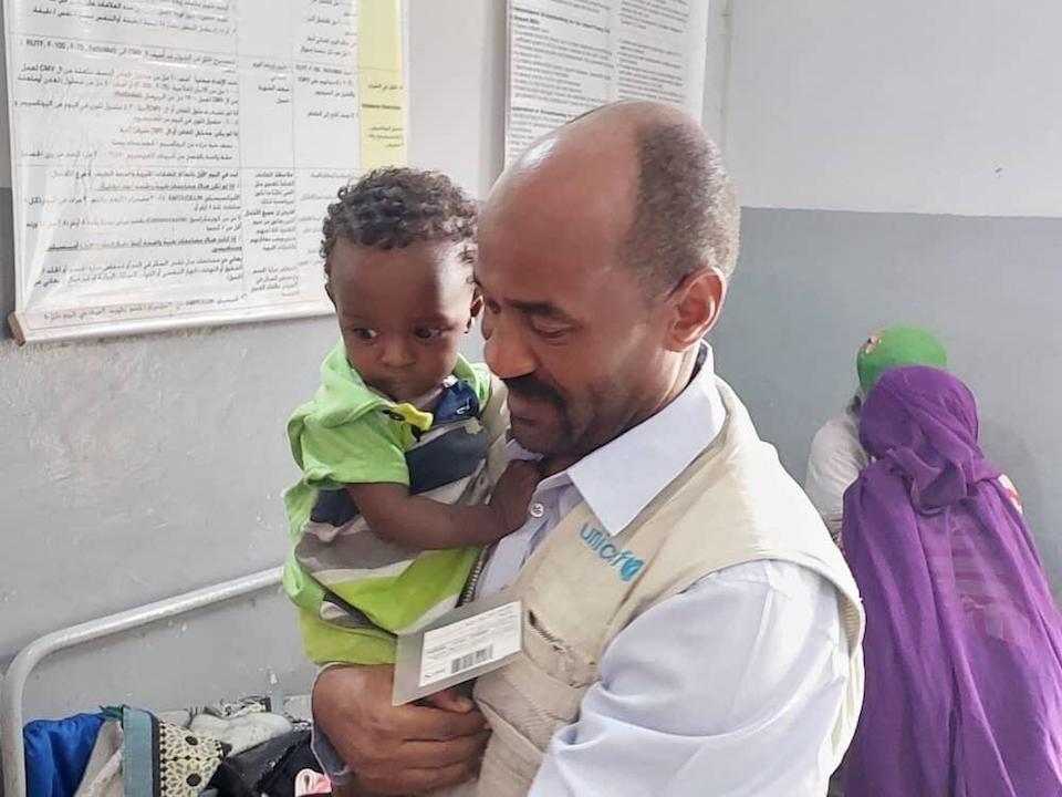 On May 29, 2023, UNICEF Nutrition Officer Mohammed Ali Elmamin carries a child recovering from severe acute malnutrition at a nutrition center in Kassala state, Sudan