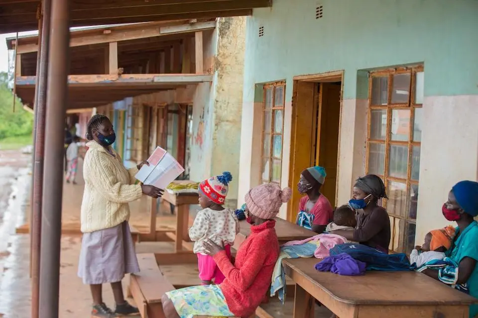 Women gather with small children to receive health advice from a community health worker in Zimbabwe.
