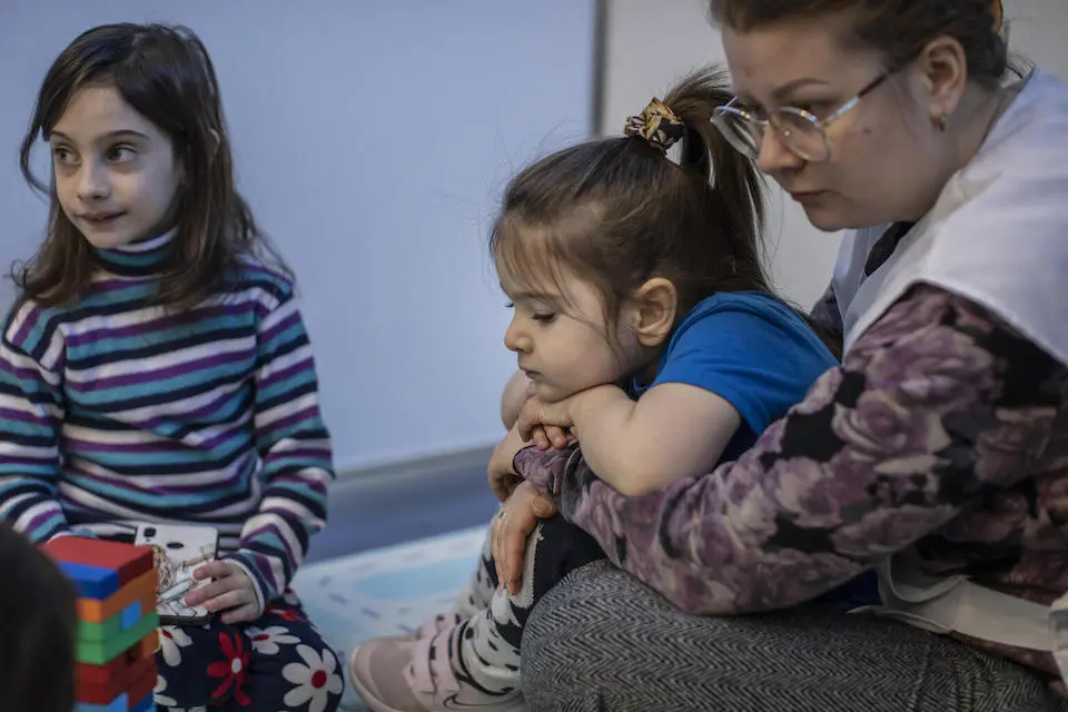 On March 20, 2022, in Chisinau, Moldova, a social worker plays with Sofia, 4, and Arina, 2, in a Child-Friendly Space set up for Ukrainian refugee children at a UNICEF-supported Blue Dot site at the Moldexpo Refugee Accommodation Center.