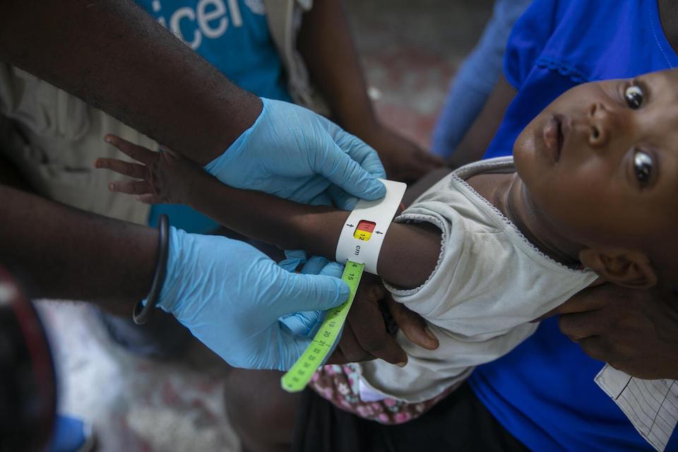A healthcare worker measures the upper arm circumference of a young girl at a malnutrition clinic run by UNICEF, in Cité Soleil, Port-au-Prince, Haiti.