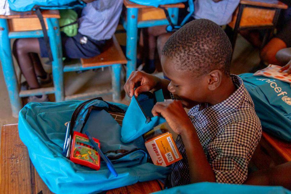 A boy opens a bag containing UNICEF-provided school supplies in Morency, Haiti.