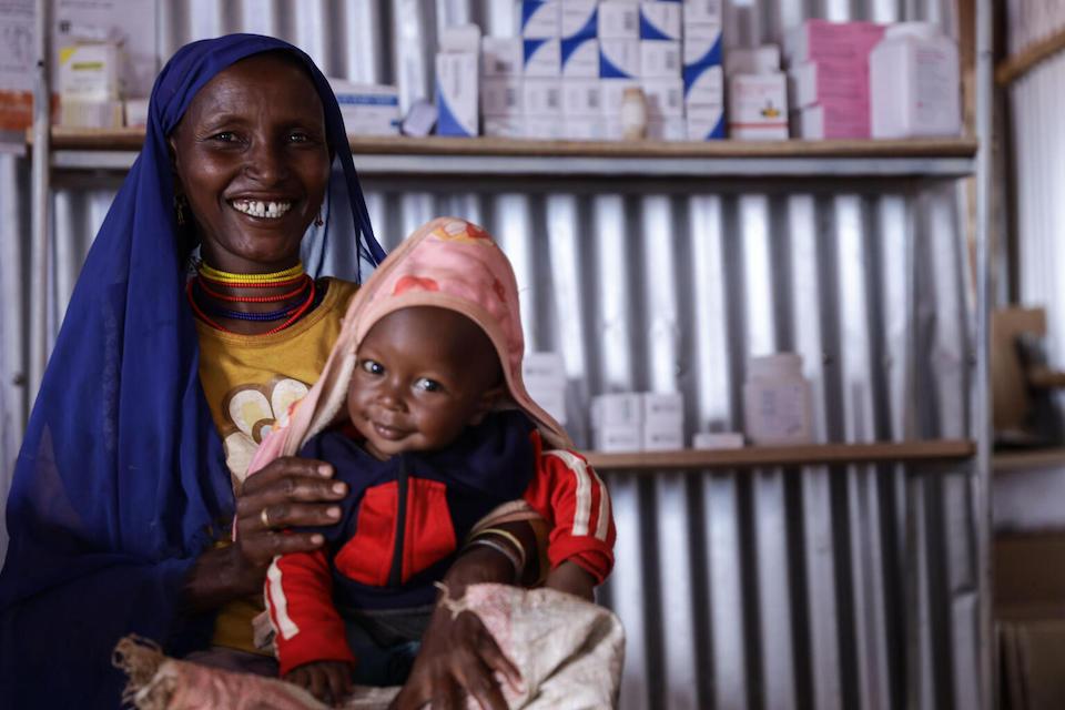 A mother in Ethiopia holds her smiling, healthy son who had been malnourished but has recovered with UNICEF's help.
