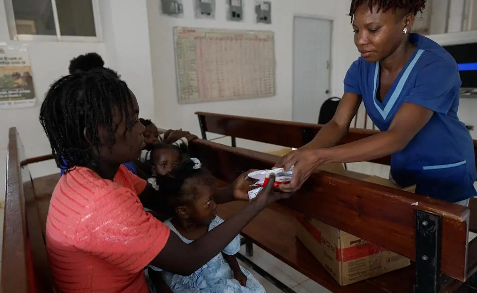 A nurse hands a mother packets of Ready-to-Use Therapeutic Food supplied by UNICEF.