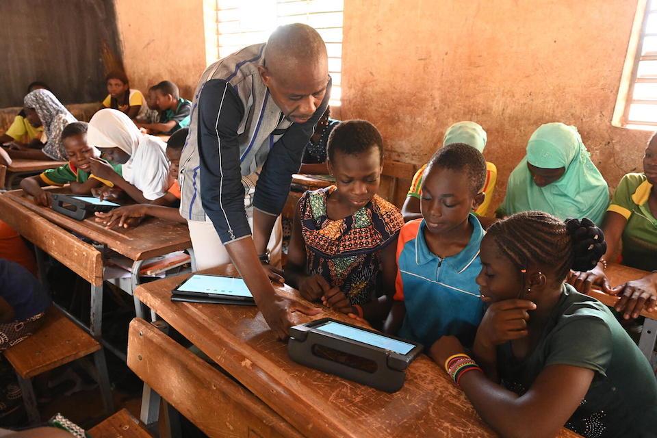 Gansonré Amadé Windemi, a teacher and father of two, helps students learning with tablets at their school in Kaya, in northeastern Burkina Faso.