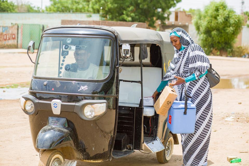 Ibtisam Abdullah Altayeb jumps into an auto rickshaw on her way to vaccinate children at a center for displaced families in Sudan.