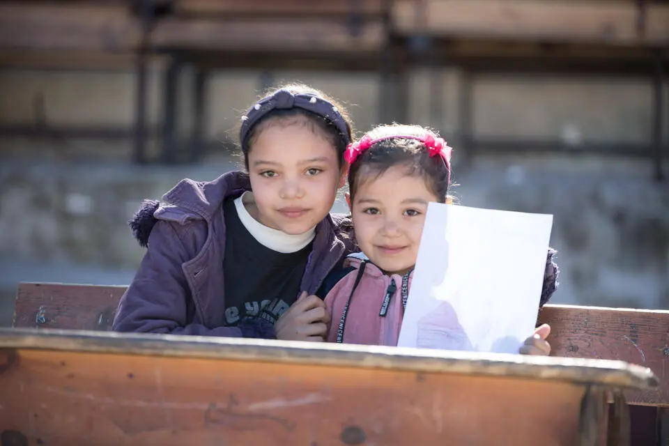 Two sisters in Syria live in a shelter after their home was destroyed in February's earthquake